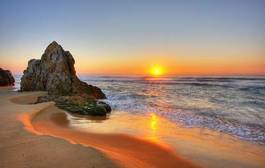 Obraz na płótnie skały na plaży o zachodzie słońca