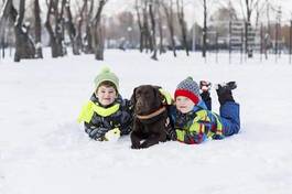 Fototapeta dzieciaki bawią się z psem na śniegu