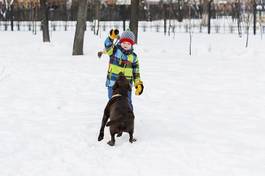 Fotoroleta chłopiec bawi się z psem na śniegu