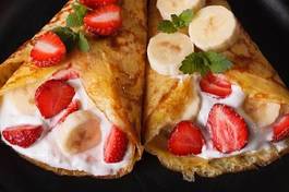 Plakat crepes with strawberries, bananas and cream close-up. horizontal