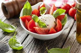 Fototapeta mozzarella cheese with basil and tomatoes in a bowl