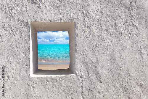 Fototapeta Małe okienko w murze z widokiem na plażę