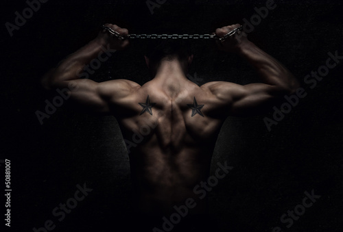 Fototapeta Muskularny sportowiec rozciąga mięśnie