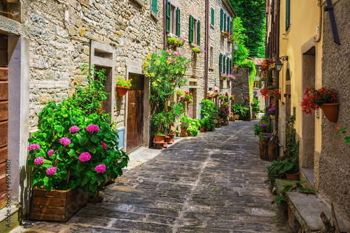 Naklejka Wąska uliczka z pięknymi kwiatami w Toskanii