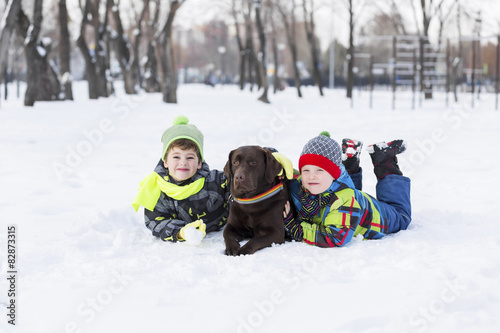 Fototapeta Dzieciaki bawią się z psem na śniegu
