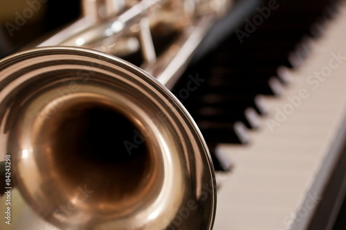 Fototapeta Trumpet segment closeup lying on piano keys