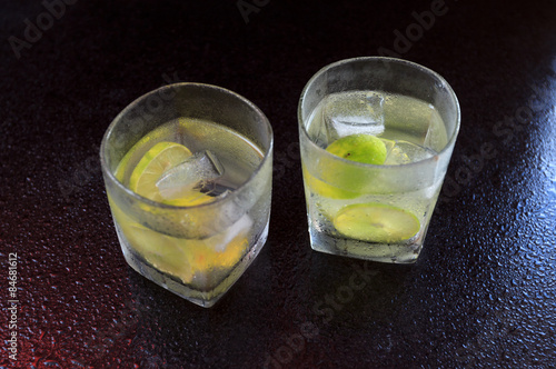 Fototapeta Lemonade served on a dark marble bar with a lime