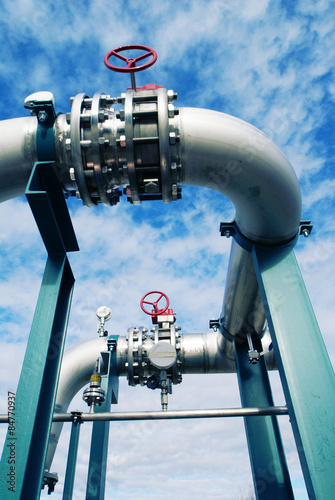 Fototapeta Industrial zone, Steel pipelines and valves against blue sky