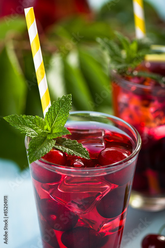 Obraz na płótnie Glass of cherry juice on blue wooden table