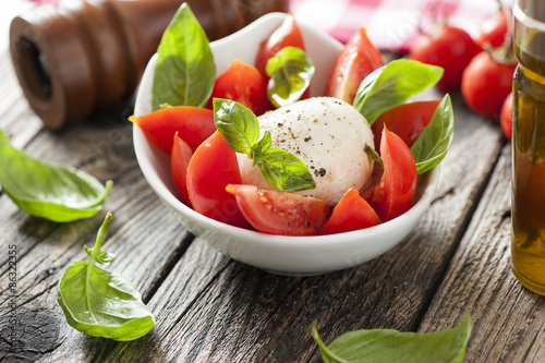 Fototapeta Mozzarella cheese with basil and tomatoes in a bowl